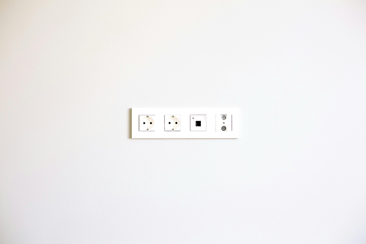 A minimalist image showcasing a modern wall outlet array on a bright white wall.