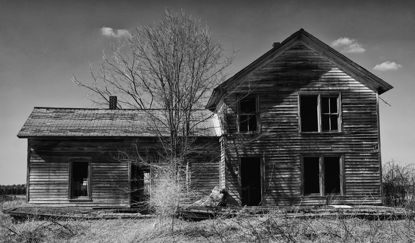 Black and white photo of an old, dilapidated wooden house in rural Marshfield WI.