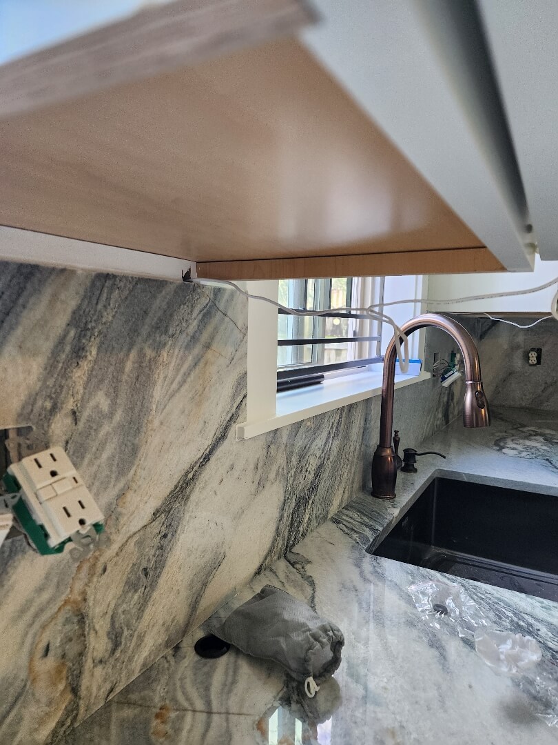 Kitchen sink area with backsplash outlets and under cabinet lighting installed for improved functionality