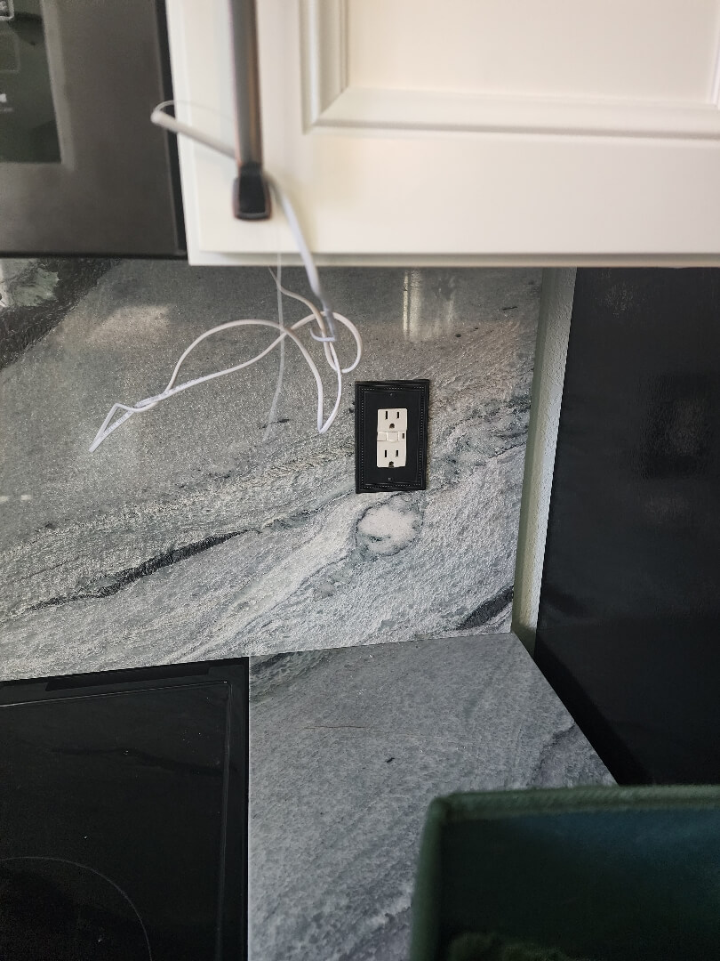 Kitchen backsplash with newly installed electrical outlet and marble countertop detail