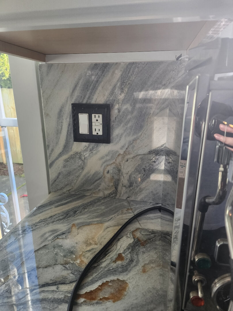 Kitchen backsplash with protective covering and dual electrical outlet installation in progress