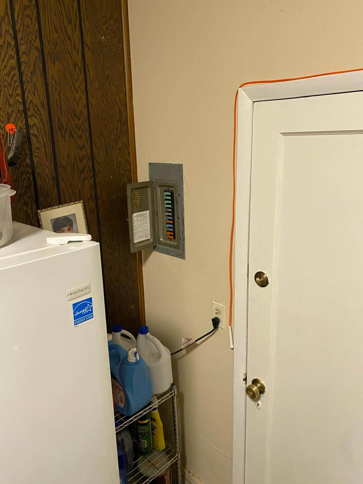 Electrical panel and meter installed on interior basement wall near utility door