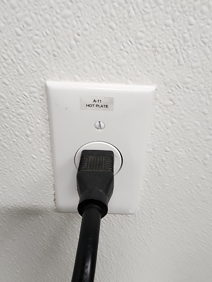 Close-up of 20-amp electrical outlet with plug connected installed in commercial space Portland OR