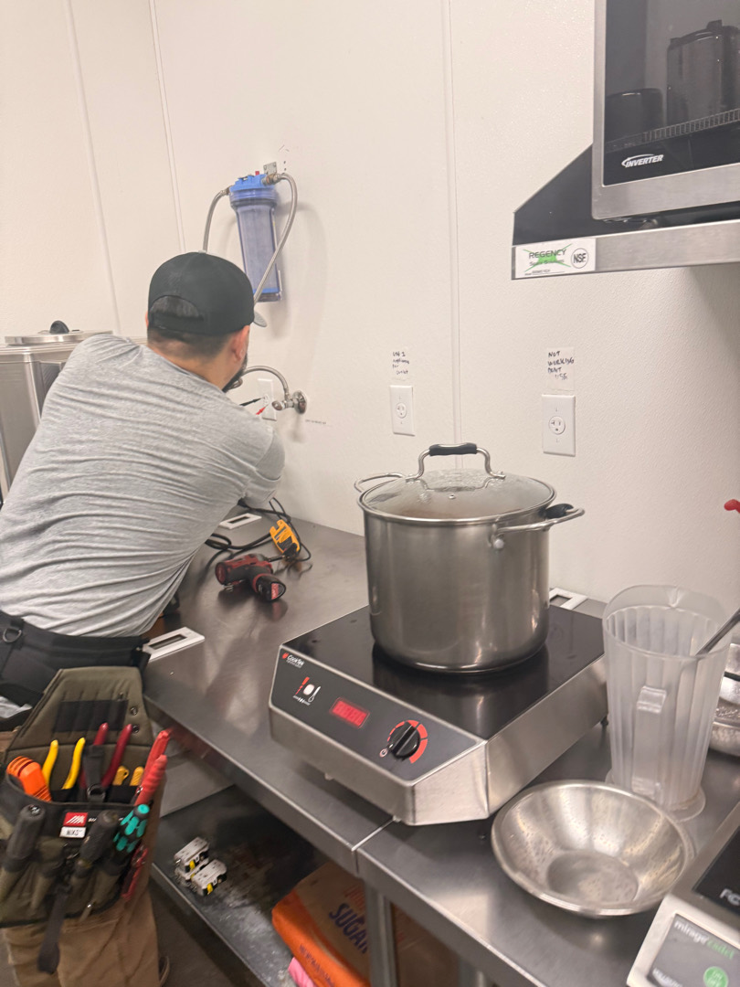 Electrician working on commercial kitchen equipment connected to upgraded 20-amp outlet in Portland OR