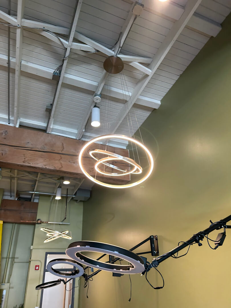 Commercial track lighting and decorative ring light fixture installed on high ceiling with exposed structure