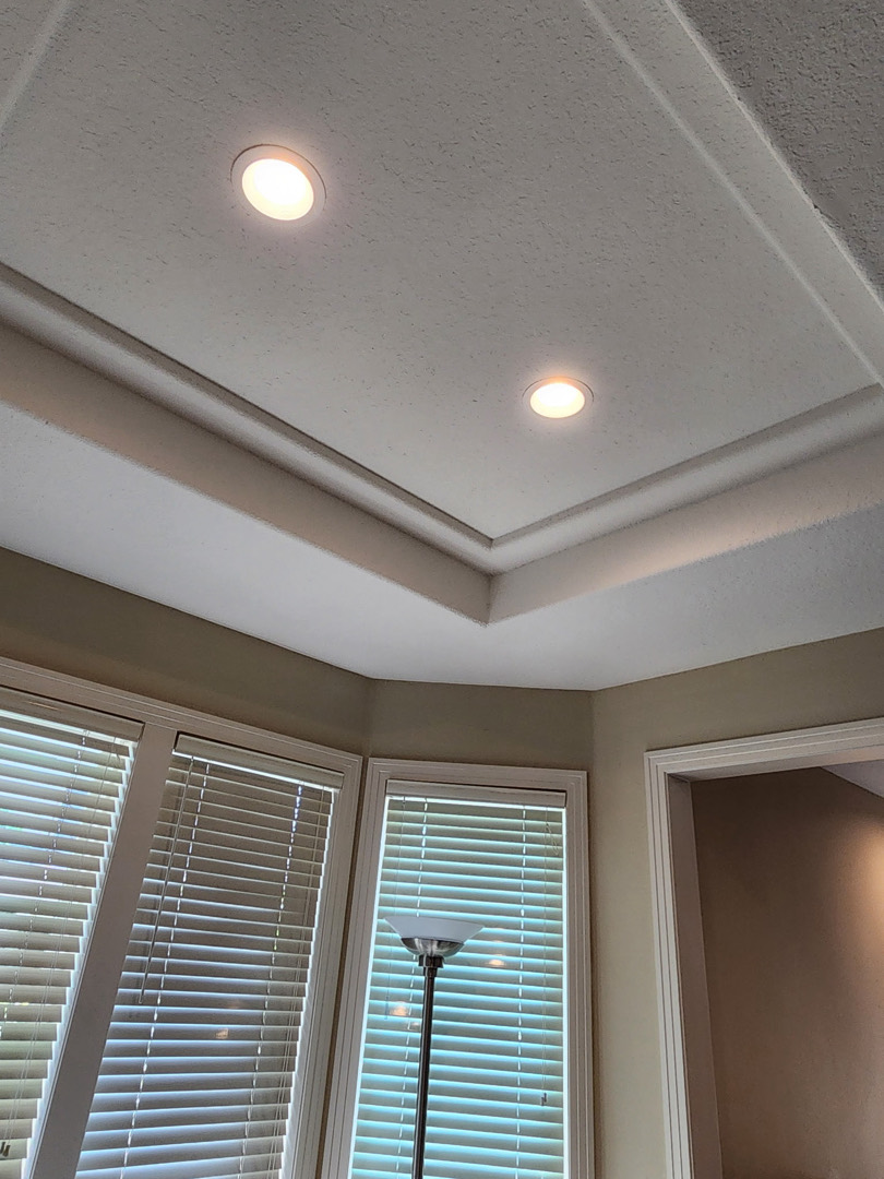Recessed ceiling lights installed in tray ceiling with crown molding detail in living space