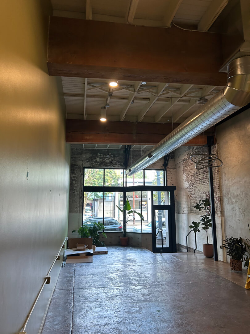 Commercial interior space with overhead lighting, exposed ceiling, and large windows for natural light