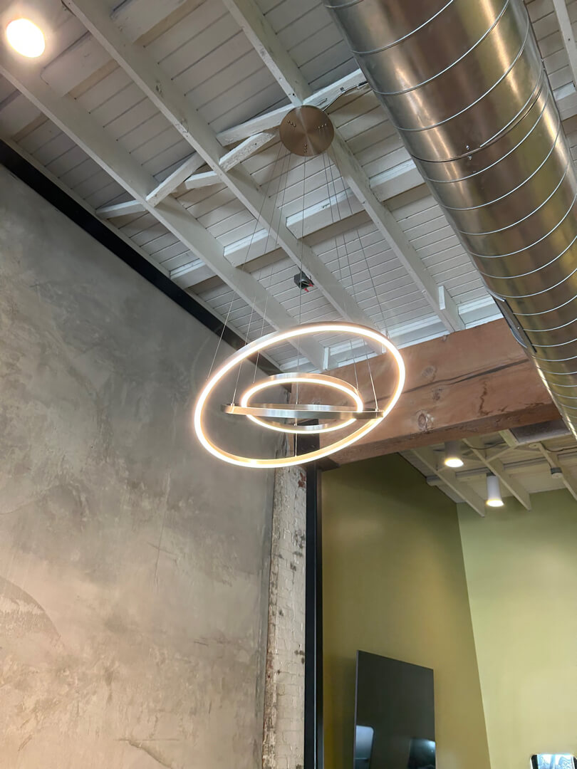 Modern circular pendant light installed on exposed ceiling with ductwork in commercial space