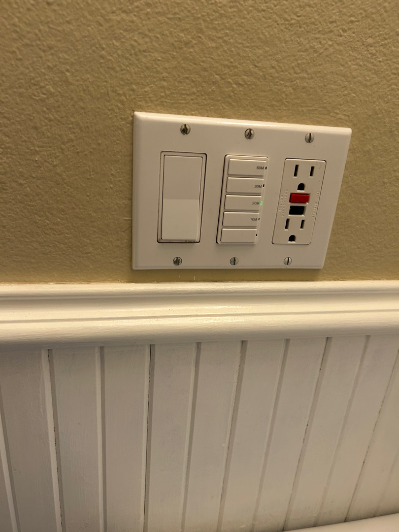 Wall-mounted control panel with multiple switches and timers installed above wainscoting
