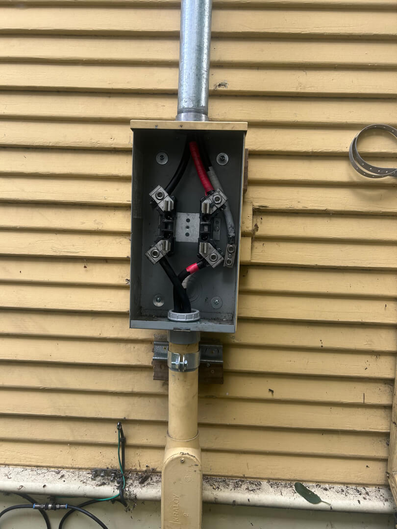 Exterior meter base with cover open showing wiring and conduit connection after repair in Portland OR