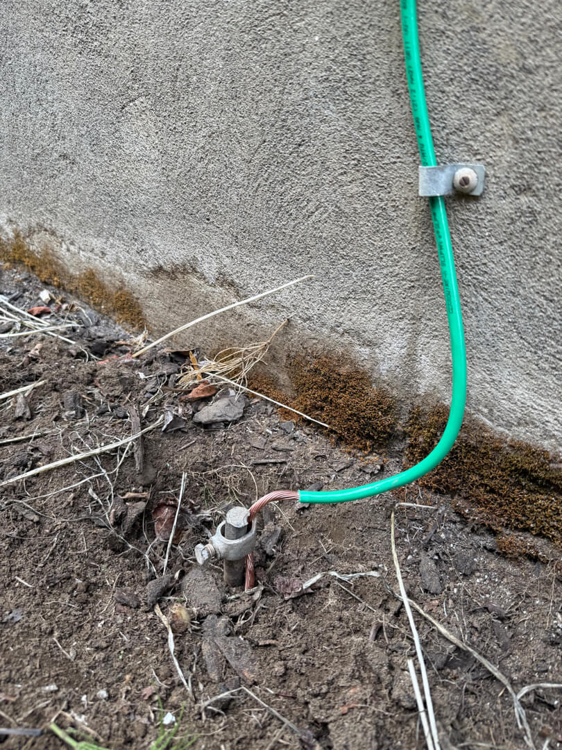 Grounding wire routed along exterior foundation during electrical panel and wiring upgrade in Portland OR