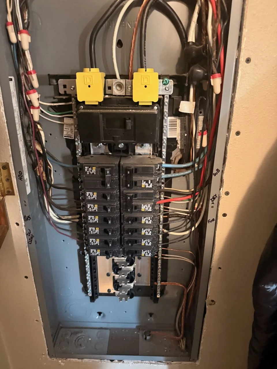 An electrical panel with its cover removed, breakers and wiring exposed for replacement.