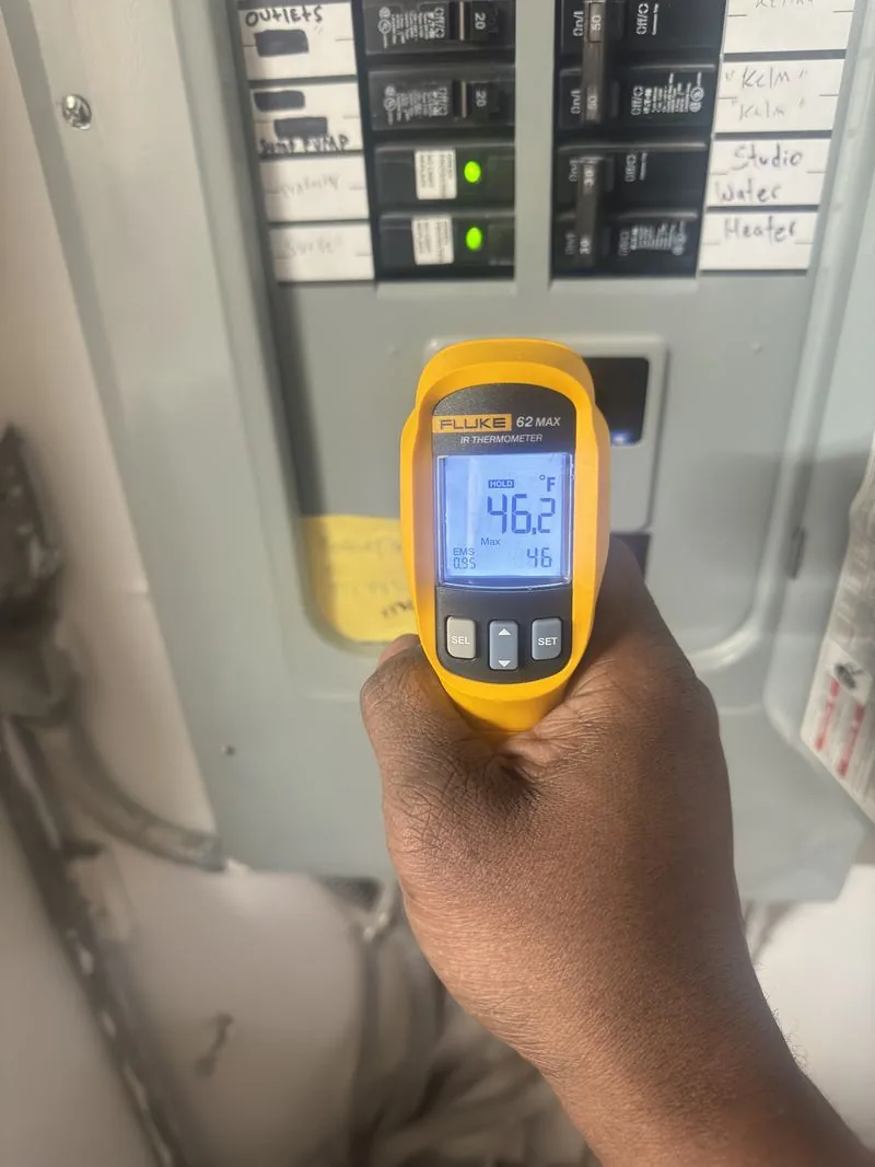 An electrician checking a panel with an infrared thermometer during a diagnostic visit.