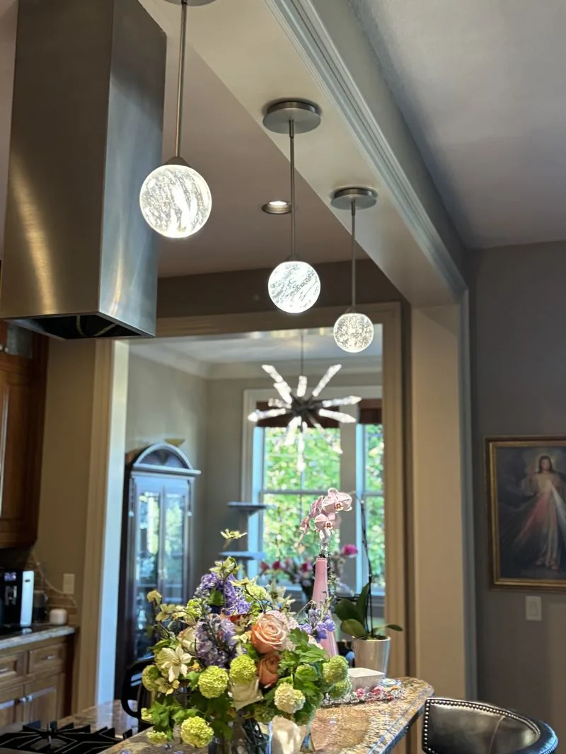 Warm pendant and chandelier lighting in a finished residential kitchen.